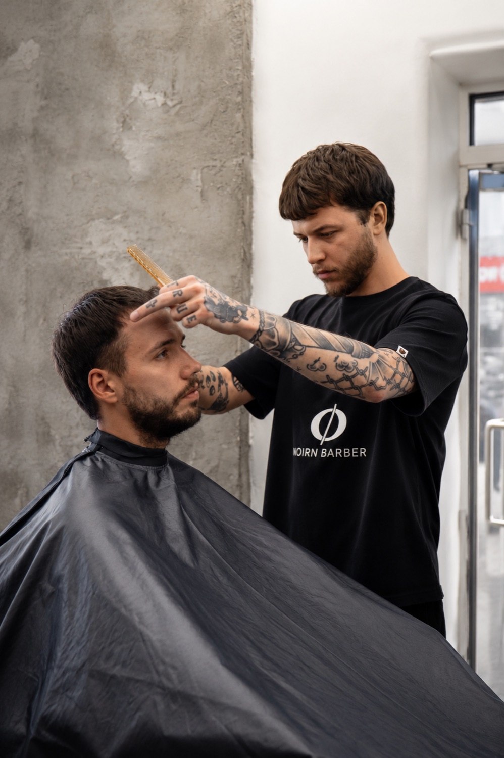 Barber upravuje vlasy klienta v NØIRN Barber