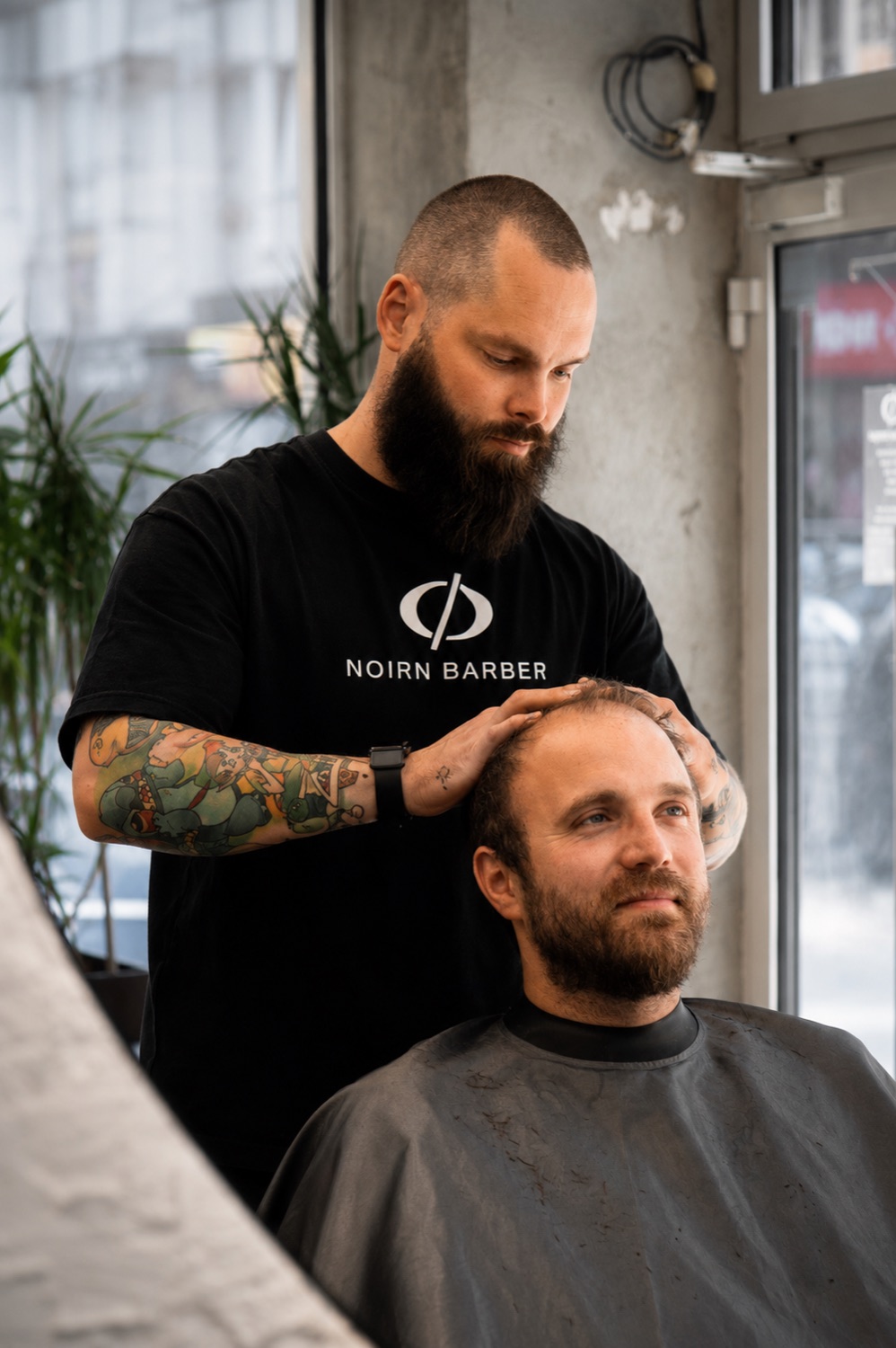 Barber upravuje vlasy bradatého klienta