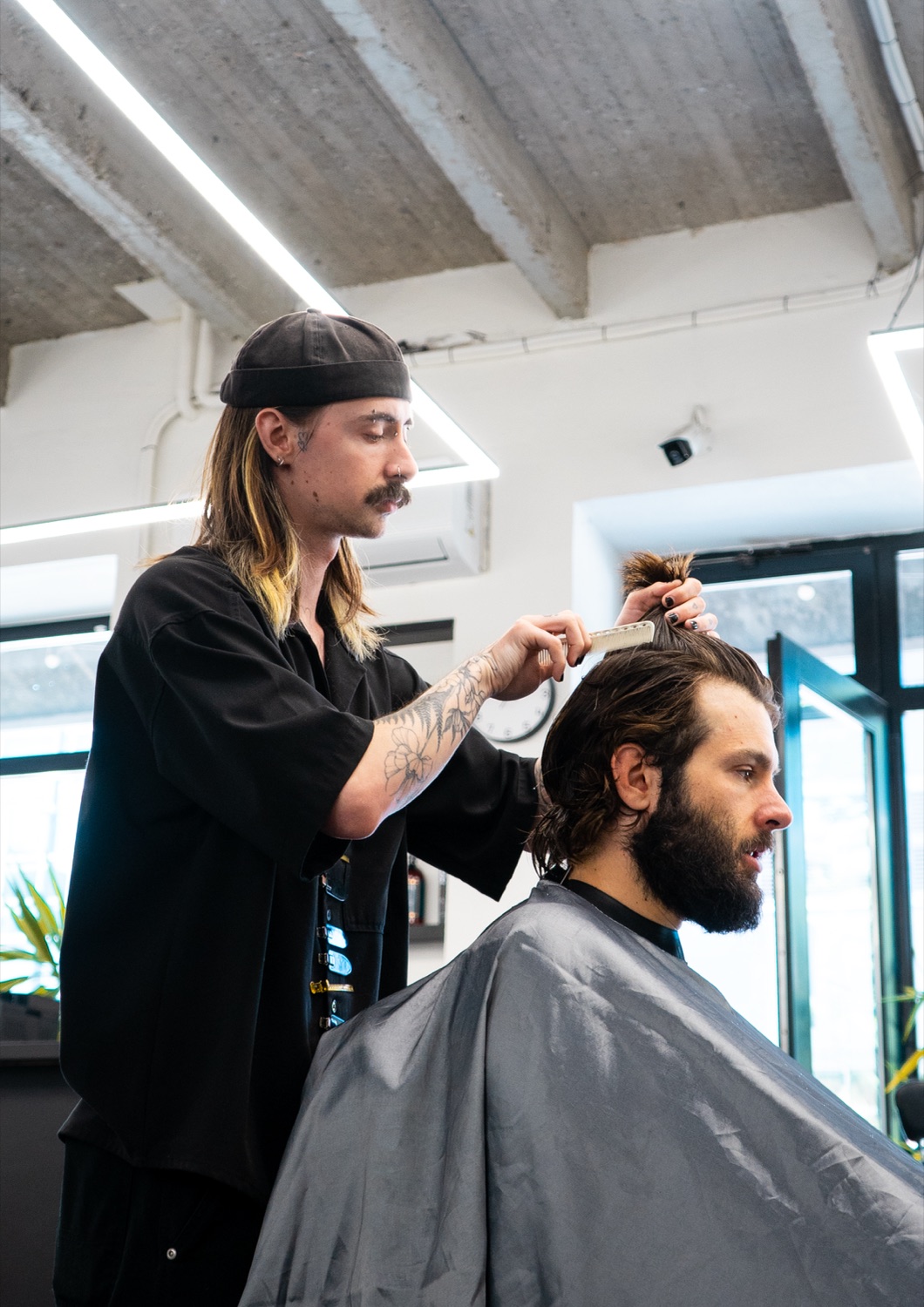 Barber češe a upravuje vlasy klienta